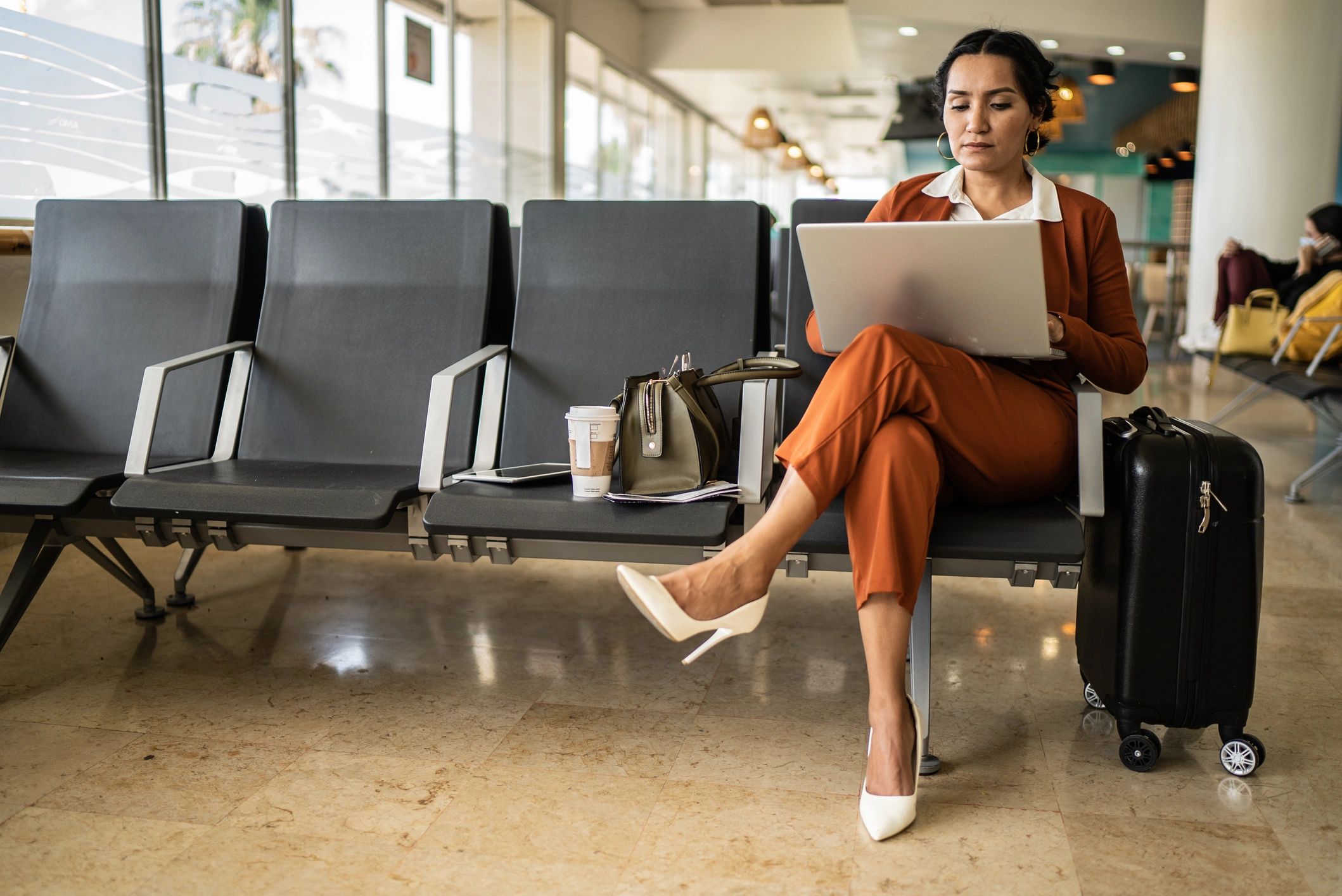 Business traveler working on a laptop in an airport departure area