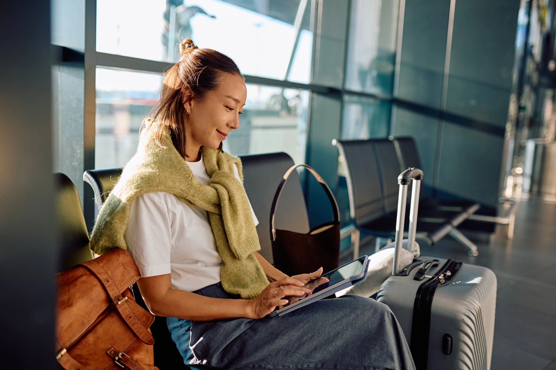 Traveler using a tablet while waiting at an airport terminal